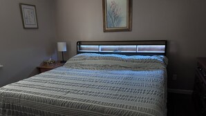 A bedroom with a bed, a nightstand, a lamp, and a dresser. - Charming 3-bedroom house in Mountain City beautiful big coy pond in backyard (Mountain City)