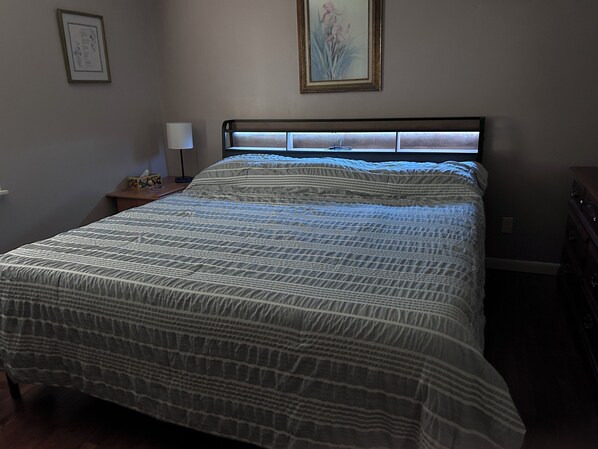 Une chambre à coucher avec un lit, une table de chevet, une lampe et une commode.