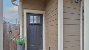 A front door with a dark-colored door, a small potted plant, and a 'hello' mat.