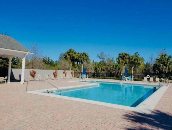 Ein Swimmingpool mit Liegestühlen und einem überdachten Pavillon.