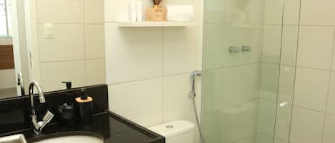 A bathroom with a black countertop sink, a toilet, and a glass-enclosed shower.