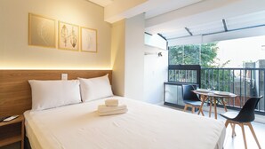 A modern hotel room with a large bed, a balcony with a table and chairs, and artwork on the wall. - Co.Next Liberdade (Sao Paulo)