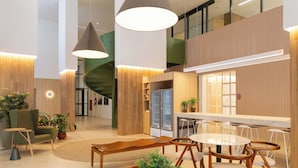 A modern interior with a spiral staircase, wooden furniture, and potted plants. - Co.Next Liberdade (Sao Paulo)