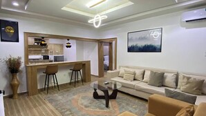 A modern living room with a sofa, a coffee table, and a kitchen area in the background. - Amazon Luxury Apartment (Enugu)
