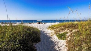 Een strandpad dat uitkomt op een strand met parasols en ligbedden.