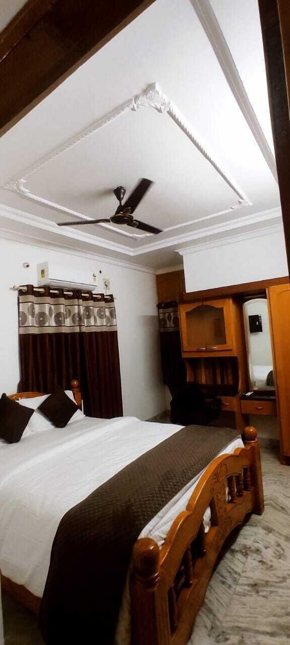 A bedroom with a bed, a ceiling fan, a wardrobe, and a mirror. - Mahuri Home Stay (Visakhapatnam)