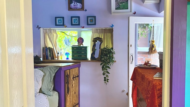 Eine kompakte Küche mit einem Holzkabinett, einem kleinen Esstisch mit roter Tischdecke und einem Fenster mit Vorhängen.