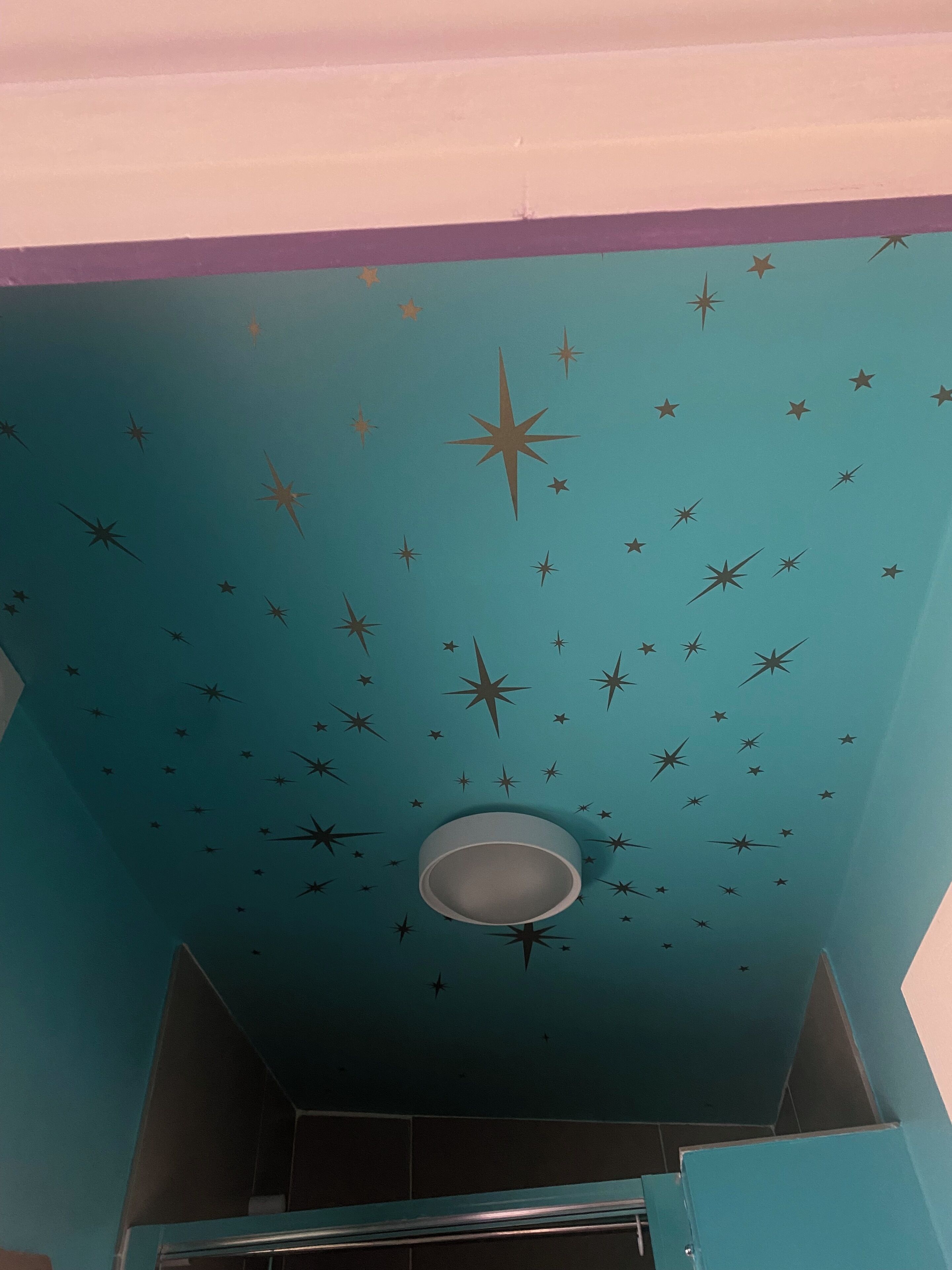 A room with teal walls and a star-patterned ceiling.