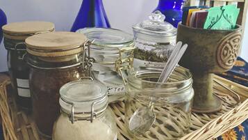 Ein Korbtablett mit verschiedenen Glasbehältern, die Zucker, Tee und andere Dinge enthalten.