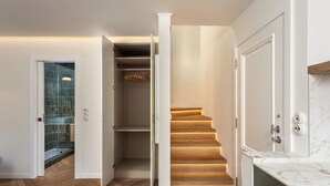 Een modern interieur met een houten trap, een douchecabine van glas en een witte kast met kledingroede.