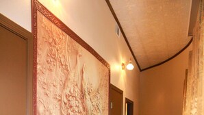 Un couloir avec un banc en bois, un mur décoratif et une porte.