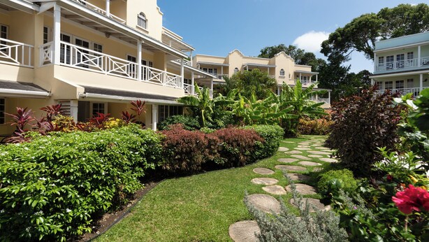 A hotel with a well-maintained garden, a stone pathway, and multiple balconies. - Charming 2-bedroom condo in fabulous Hastings area (Hastings)