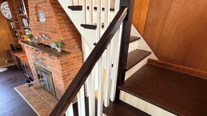 A staircase with wooden steps and white railings, leading to a brick fireplace with a sign that reads 'RELAX YOURSELF.'