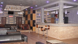 Un hall d’entrée moderne avec des sièges en cuir, un bar et un écran de télévision.