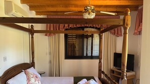 A four-poster bed with a wooden headboard, a green throw blanket, and rolled towels on the side. - VILLA AURA (Πλάτρες)