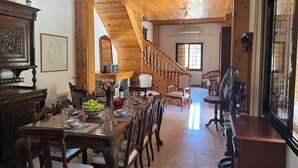 A spacious dining area with a wooden staircase leading to an upper level. - VILLA AURA (Πλάτρες)