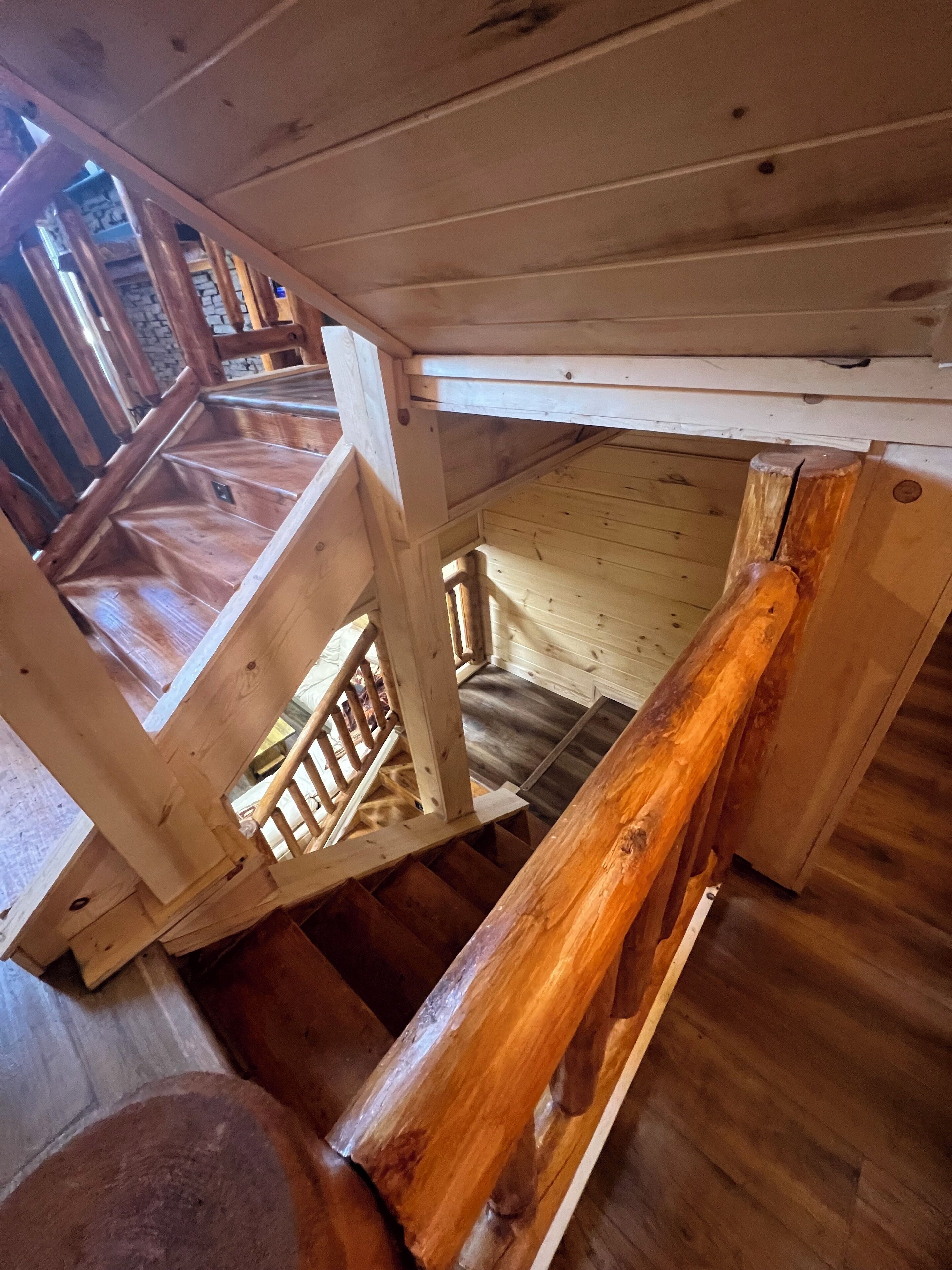 Un escalier en bois, doté d’une rampe, mène à un niveau inférieur.