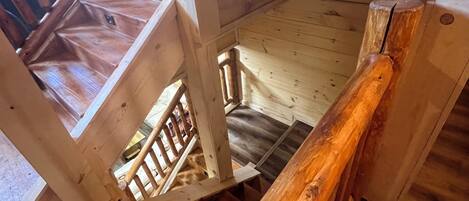 Un escalier en bois, doté d’une rampe, mène à un niveau inférieur.