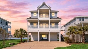 A multi-story building with balconies, a covered entrance, and a view of the water. - Bayfront 4BR Retreat in Pointe West with Hot Tub Sleeps 12 (Galveston)