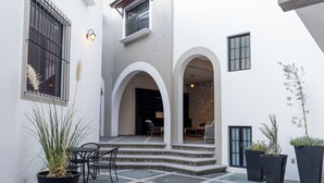 A courtyard with a tiled floor, outdoor seating, and potted plants. - Traspatio hotel Boutique  (Bernal)