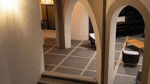 A staircase leading to a covered outdoor area with a seating arrangement and a wall-mounted light fixture. - Traspatio hotel Boutique  (Bernal)
