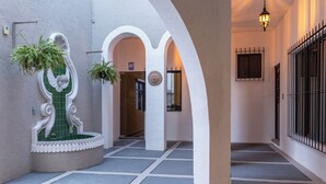 A corridor with white walls, green-tiled niches, and hanging plants. - Traspatio hotel Boutique  (Bernal)