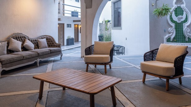 A cozy lounge area with a sofa, two armchairs, and a wooden table. - Traspatio hotel Boutique  (Bernal)