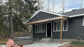 Un patio con un hogar, dos sillas Adirondack y un jacuzzi.