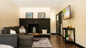 Una sala de estar moderna con un sofá modular, una chimenea, un televisor de pantalla plana y un pasillo que conduce a otra habitación.