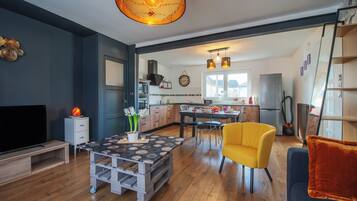 Un salon moderne avec un téléviseur, une table basse, un fauteuil jaune et un canapé.