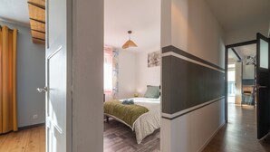 A room with a bed, a bedside table, a lamp, and a window with curtains. - Le Jovia - Cour extérieure - Wifi (Laval)