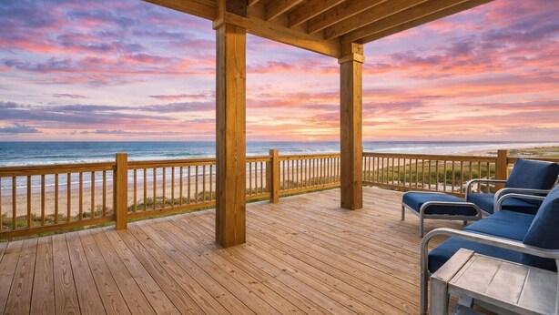 A wooden deck with a view of the ocean and a sunset. - Beachfront | Hot Tub | Putt Putt | Fire Pit (Gilchrist)