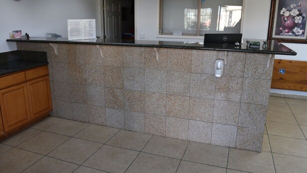 A kitchen with a granite countertop, wooden cabinets, a window, and a door. - Corcoran Inn (Corcoran)