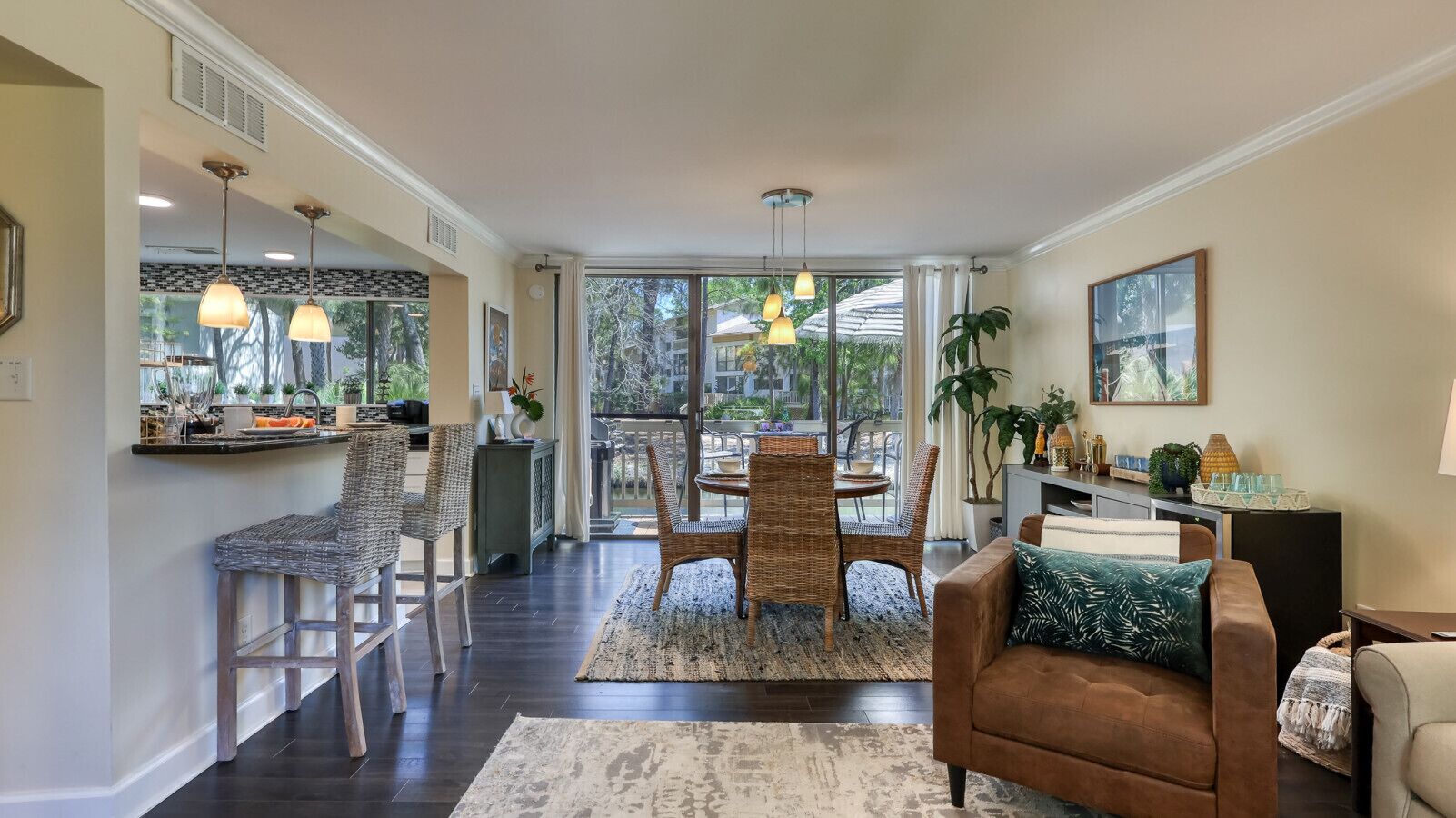 A spacious living area with a dining table and chairs, a sofa, and a kitchen area with a bar counter.