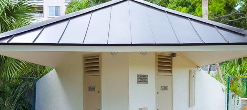Um pequeno edifício térreo com telhado inclinado e duas portas, uma das quais possui uma placa acima.
