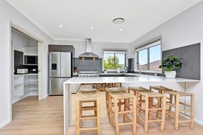 A modern kitchen with a central island, built-in appliances, and a large window.