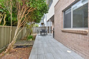 Een terras met een tafel en stoelen, een bakstenen muur en een houten hek.