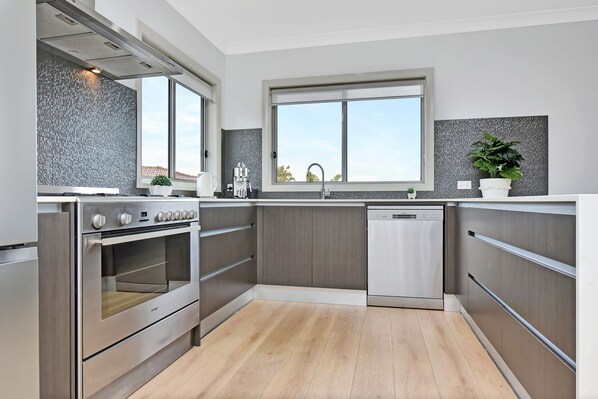 Een moderne keuken met inbouwapparatuur, een raam en uitzicht op buiten.