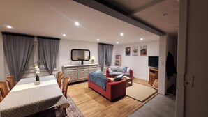 A modern living room with a dining area, wooden flooring, and a TV. - new house, beach at 5 minutes, 3 bedrooms, large garden, terrace, bike provided. (Pont-Croix)