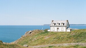 A coastal house with a sloped roof, situated on a grassy hill overlooking the sea. - new house, beach at 5 minutes, 3 bedrooms, large garden, terrace, bike provided. (Pont-Croix)