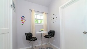 A small room with two black leather chairs around a white table, a clock on the wall, and a window with curtains. - Beautiful 1-bedroom apartment in amazing Buckleys with AC, WiFi (Buckleys)