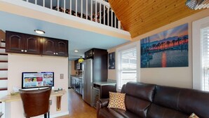 A spacious living area with a leather sofa, a dining table, and a kitchen in the background.