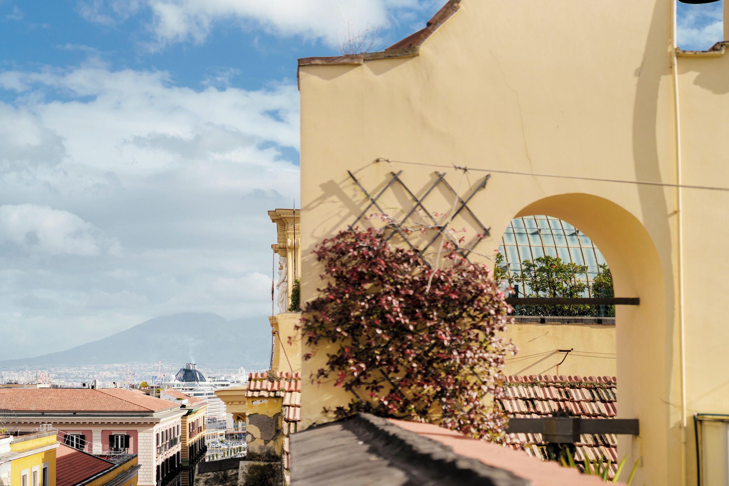 A yellow building with a large arched window and a view of a mountain.