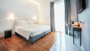 Une chambre à coucher moderne avec un lit, des tables de chevet, un bureau et un téléviseur.