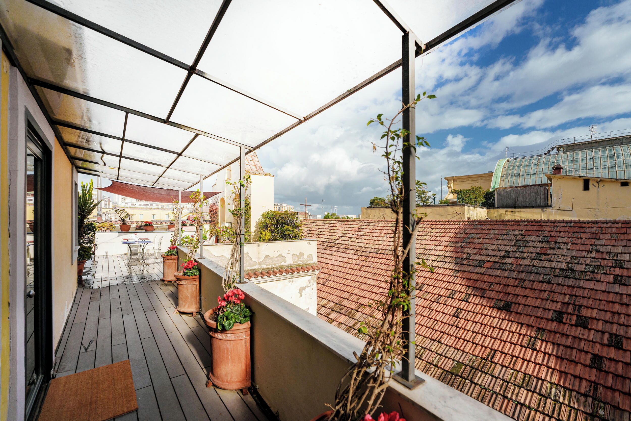 Un balcone esterno coperto con piante in vaso e vista sulla città.
