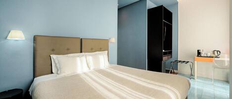Una habitación de hotel con una cama grande, un escritorio con silla y un armario.