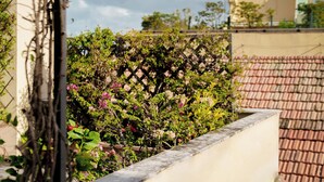 Un jardin avec une clôture en treillis, un mur et un toit recouvert de tuiles en arrière-plan.