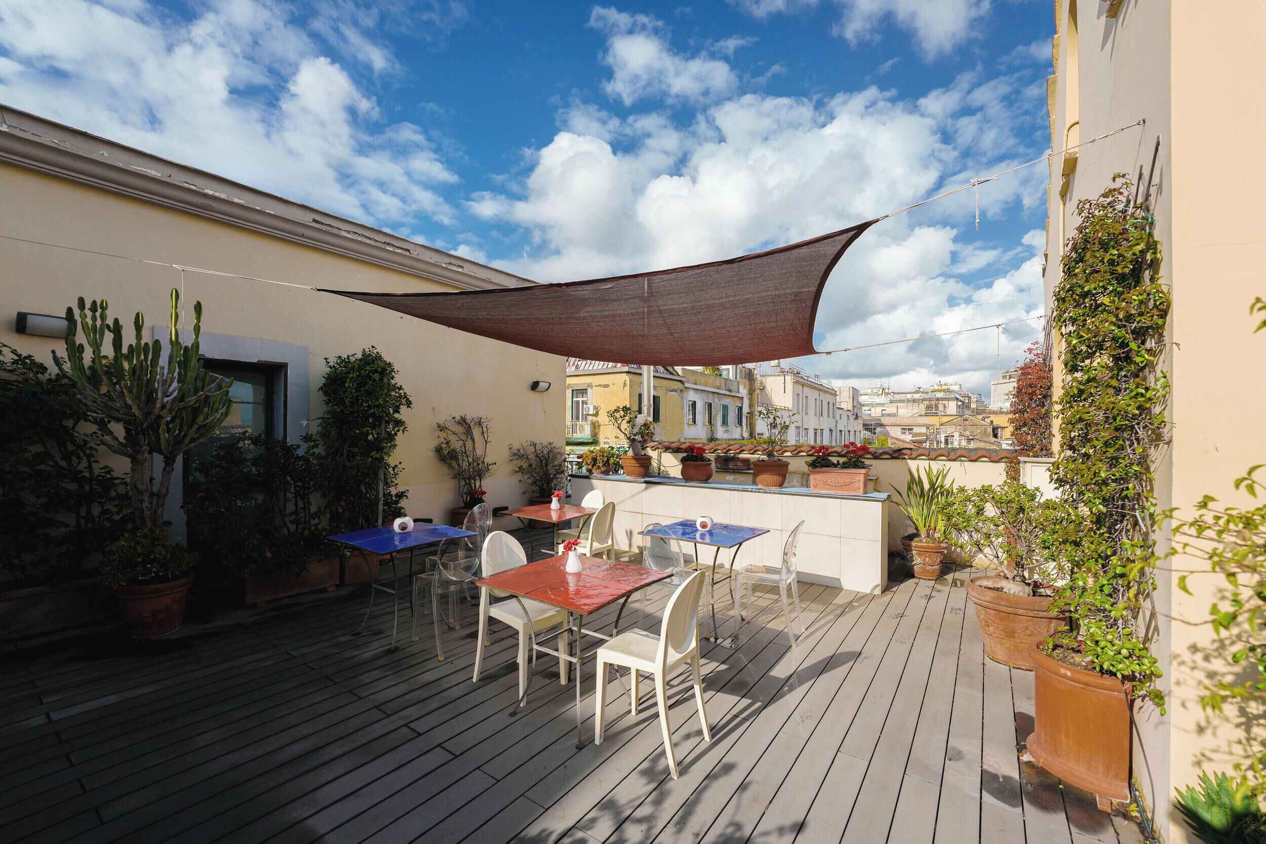 A rooftop patio with outdoor seating, potted plants, and a view of the cityscape.