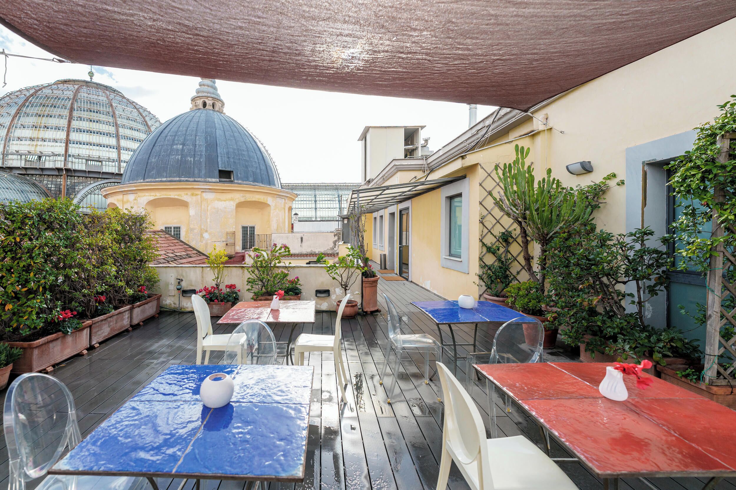 An outdoor patio with tables and chairs, a blue dome structure, and potted plants.