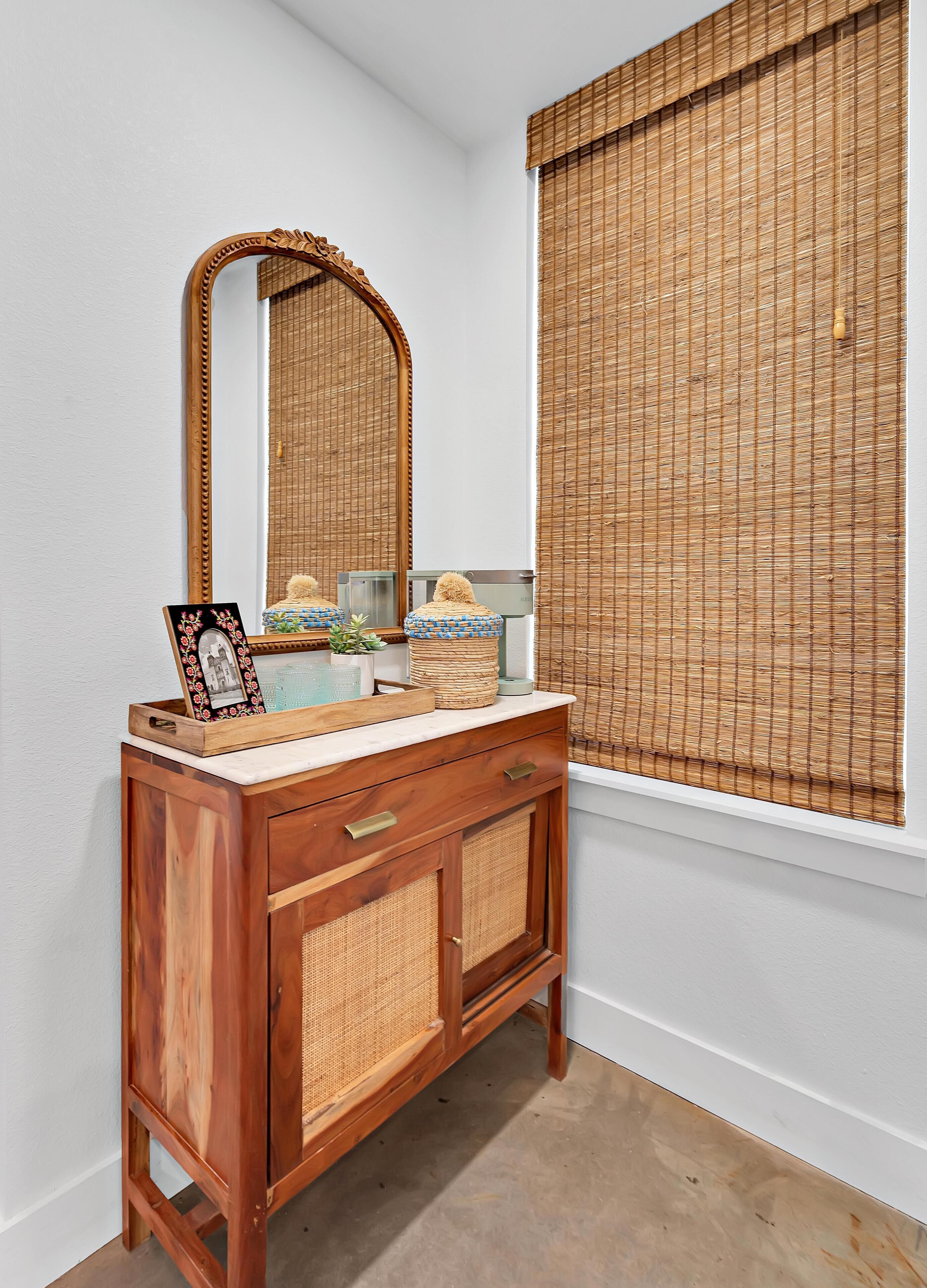 A wooden vanity with a mirror, a framed photo, and decorative items.